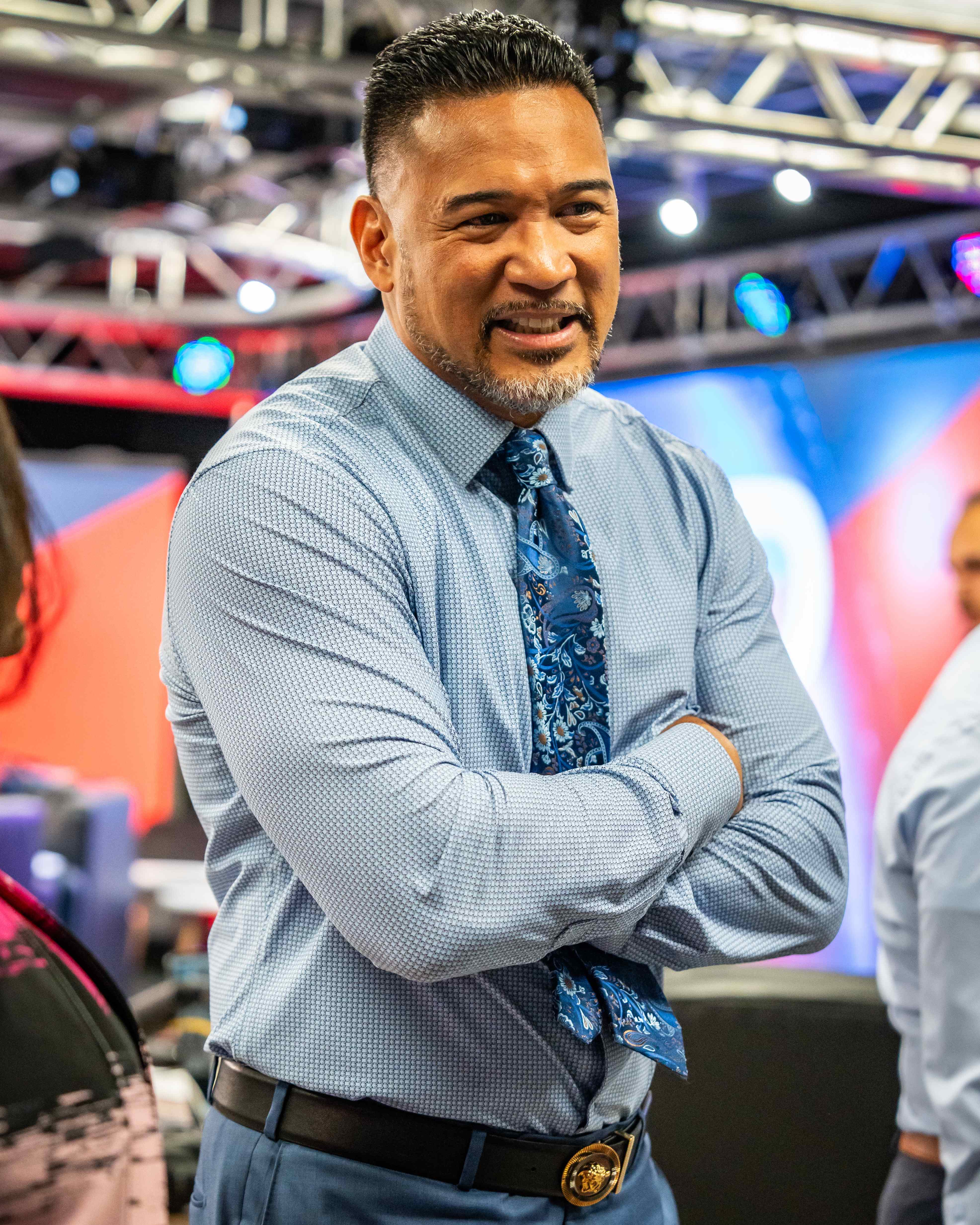 Man smiling with arms crossed at broadcast event