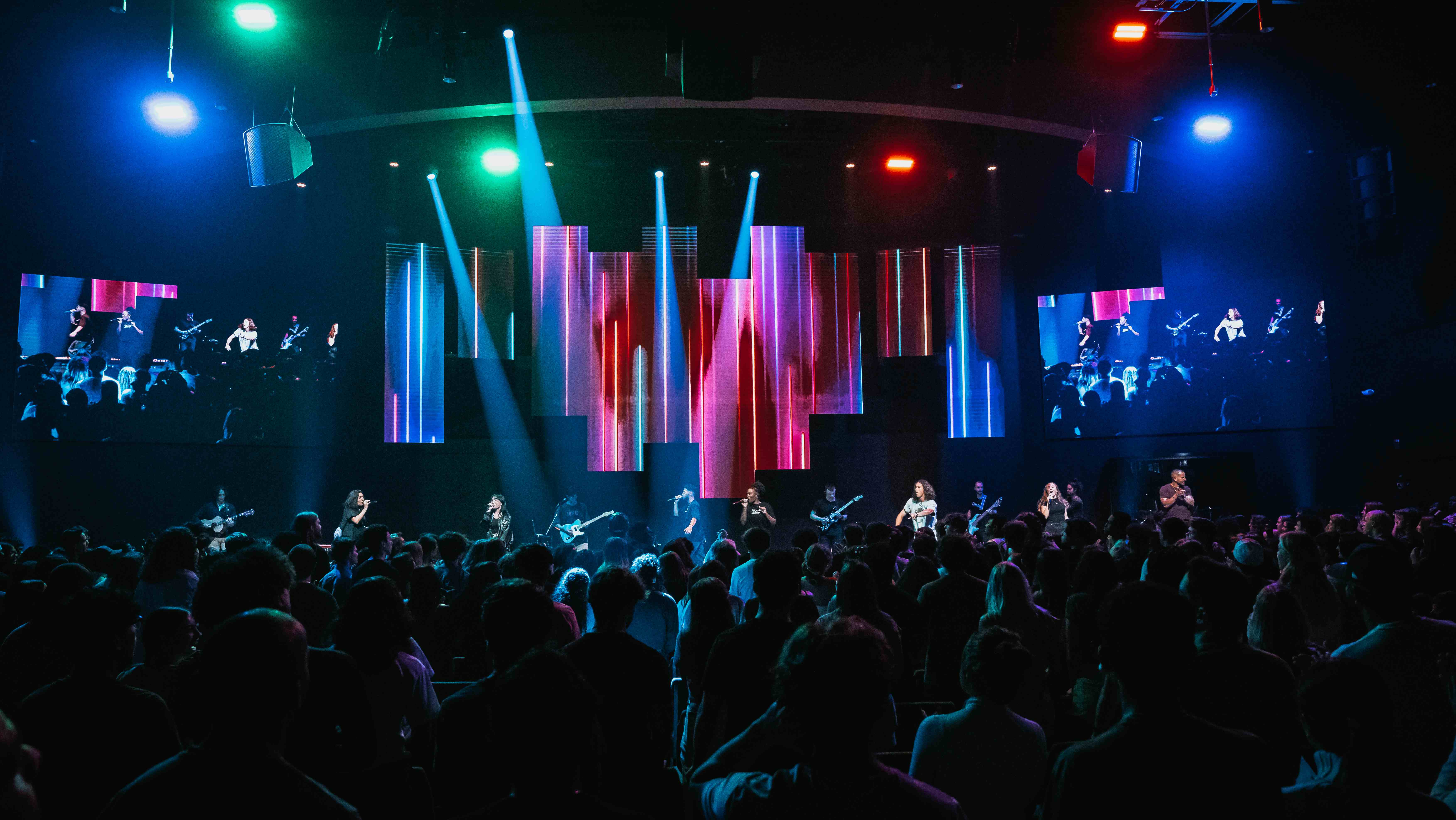 Wide shot of worship concert with colorful LED stage panels and large crowd