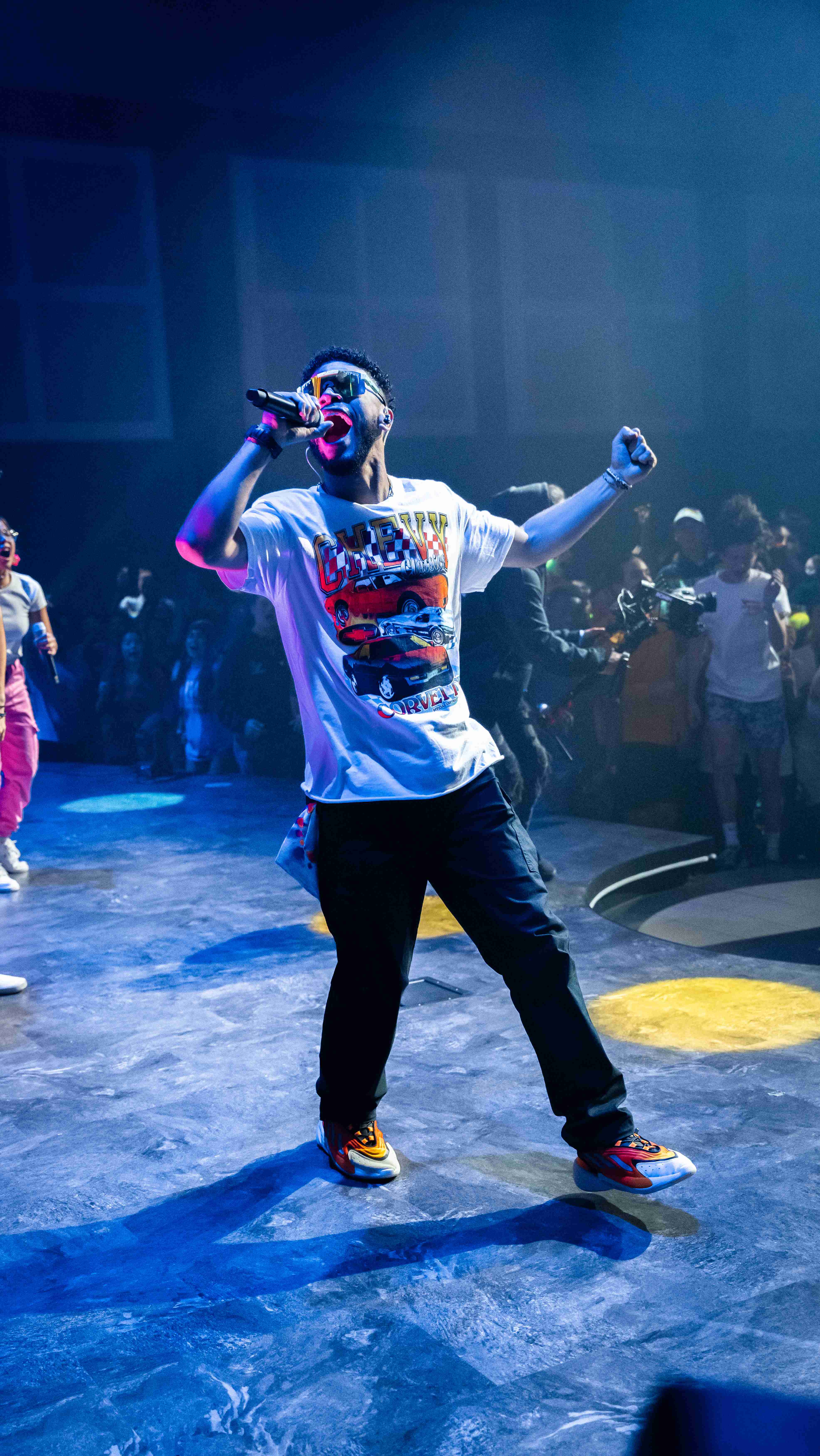 Performer singing on blue-lit stage in front of a crowd