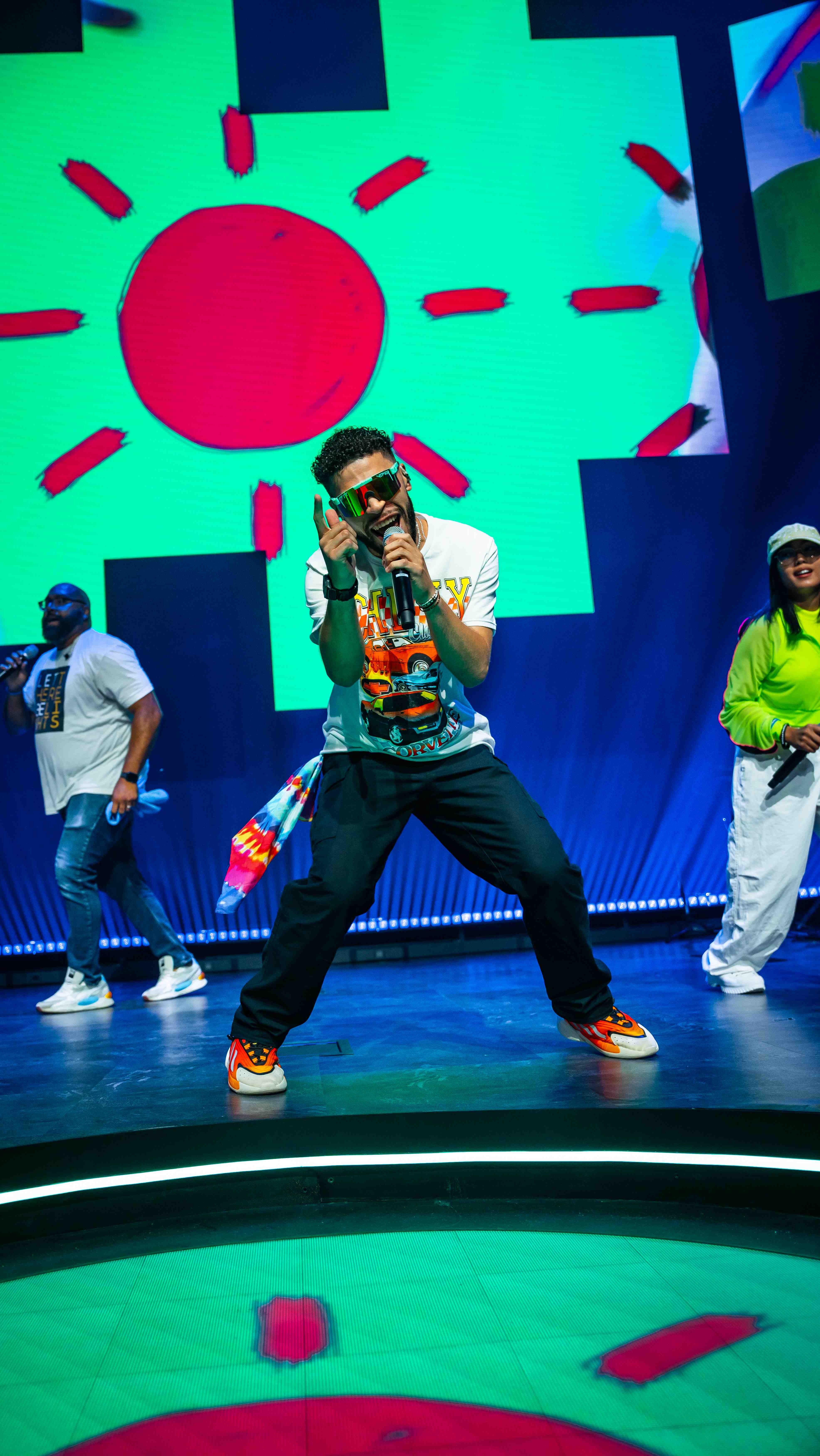 Energetic performer on stage at youth event with vibrant colorful backdrop