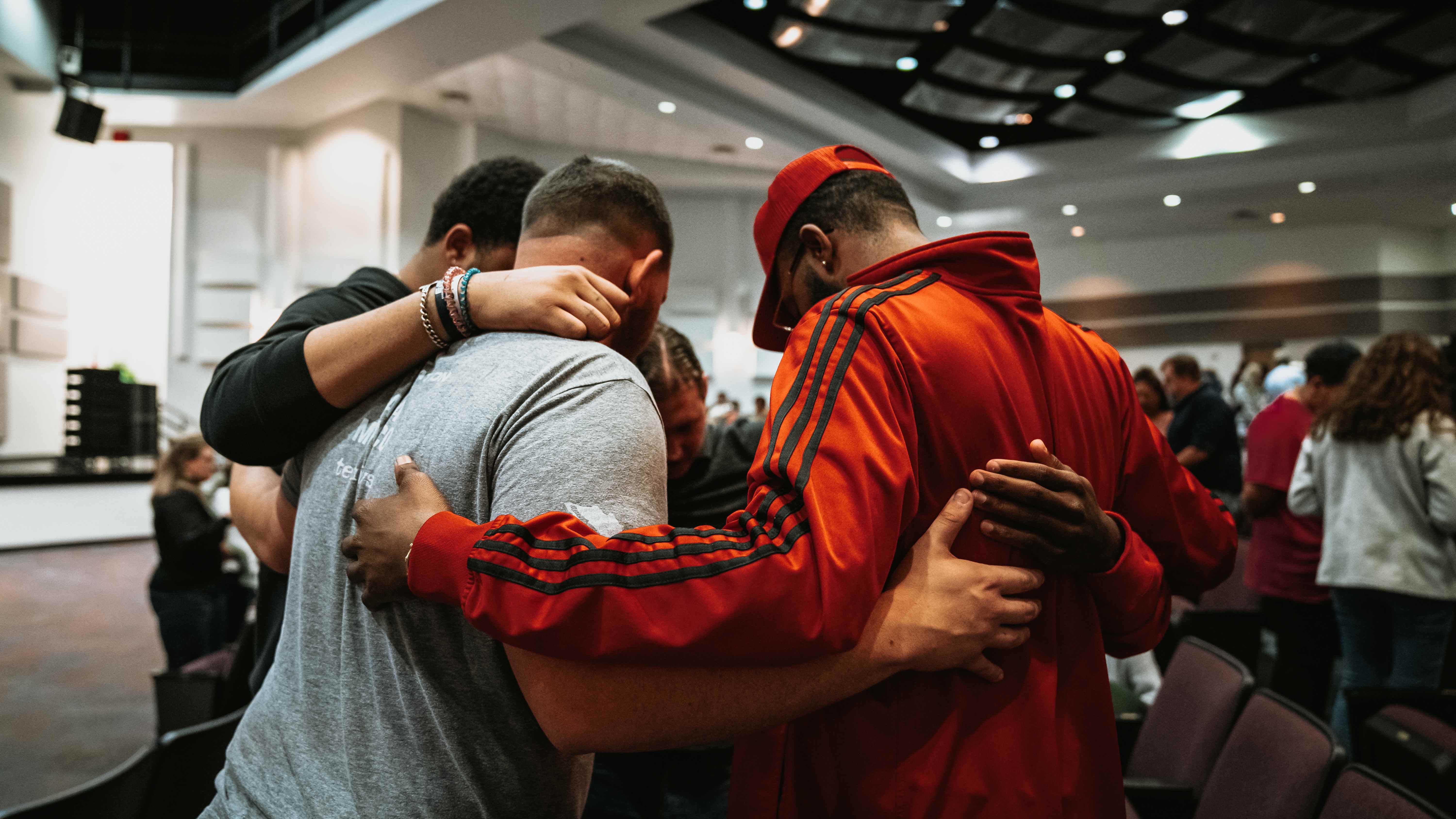 Group prayer huddle during ministry service in church auditorium