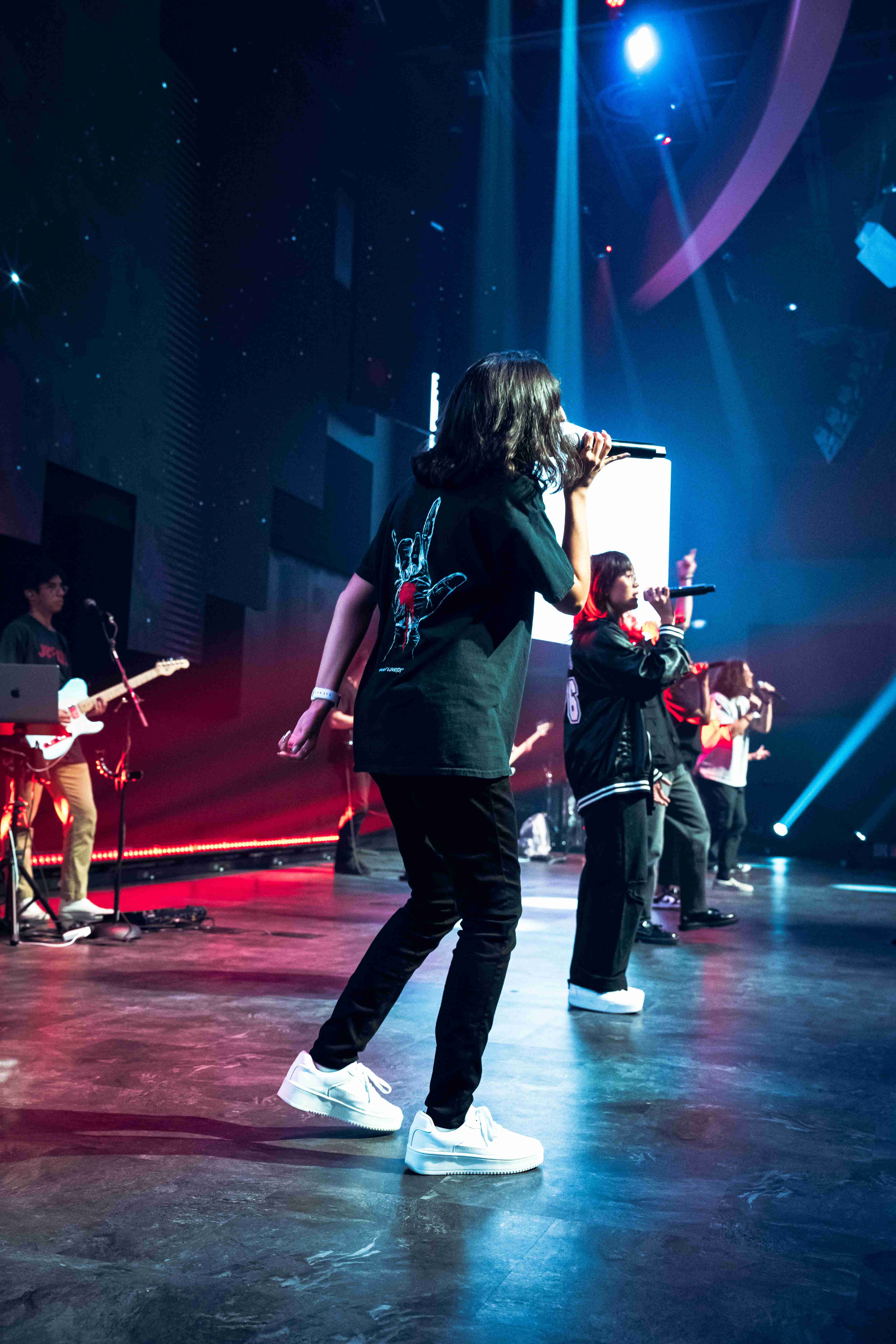 Female singer performing from behind view with red and blue stage lighting