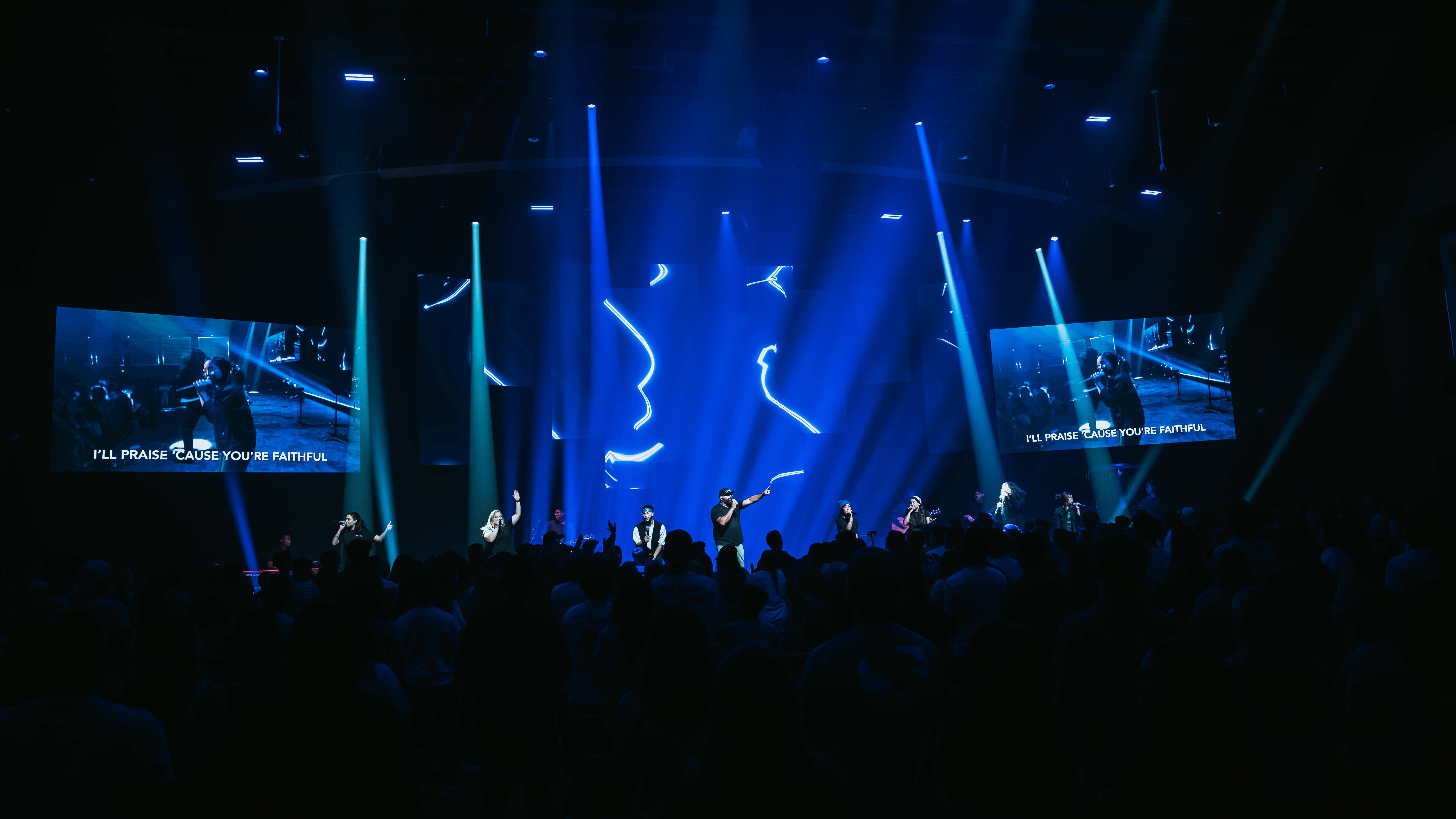Worship team performing under dramatic blue stage lights